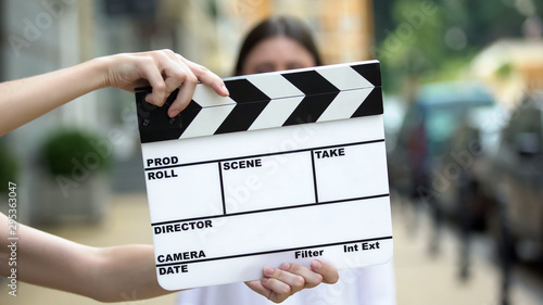 Fotografía Hands holding clapperboard in front of young woman, movie scene, production