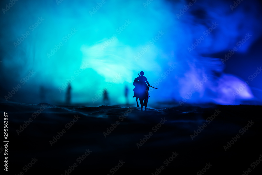 World war officer (or warrior) rider on horse with a sword ready to fight and soldiers on a dark foggy toned background. Battle scene battlefield of fighting soldiers. World war officer (or warrior) rider on horse with a sword ready to fight and soldiers on a dark foggy toned background. Battle scene battlefield of fighting soldiers.