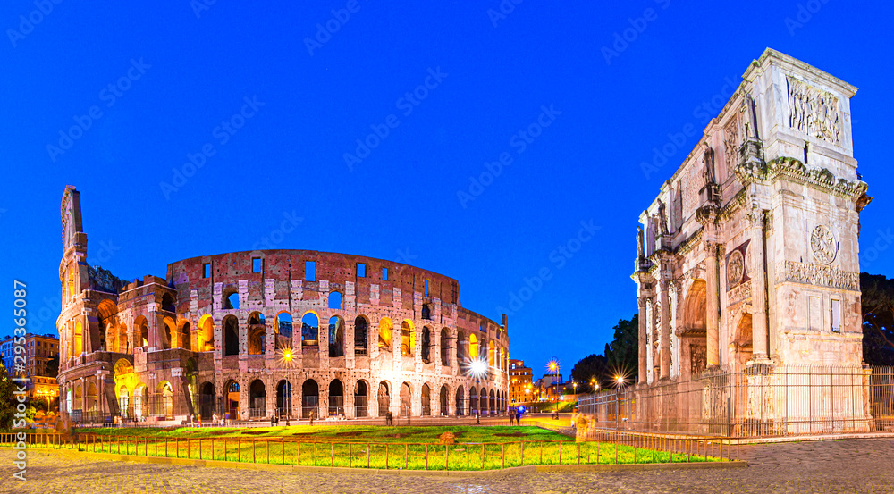 Rome, Italy: Night view of The Arch of Constantine next to the Colosseum after sunset over a blue sky.