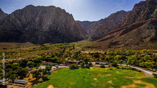 Beautiful view of famous Spring Mountain Ranch State Park near Las Vegas and Red Rock Canyon, Nevada during autumn with pink and red rock mountains, blue sky, green trees and grass, and purple hills
