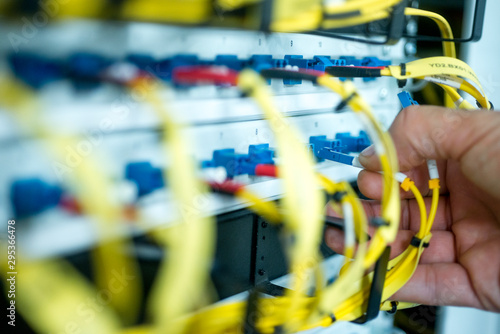 human hand fixing fiber glass cable into control panel