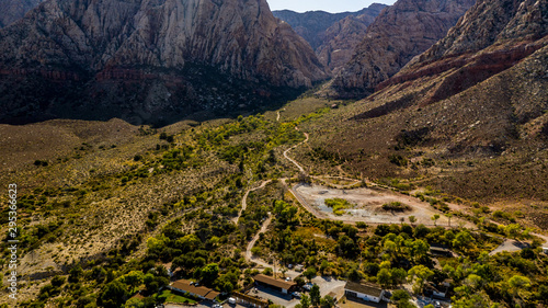 Beautiful view of famous Spring Mountain Ranch State Park near Las Vegas and Red Rock Canyon, Nevada during autumn with pink and red rock mountains, blue sky, green trees and grass, and purple hills