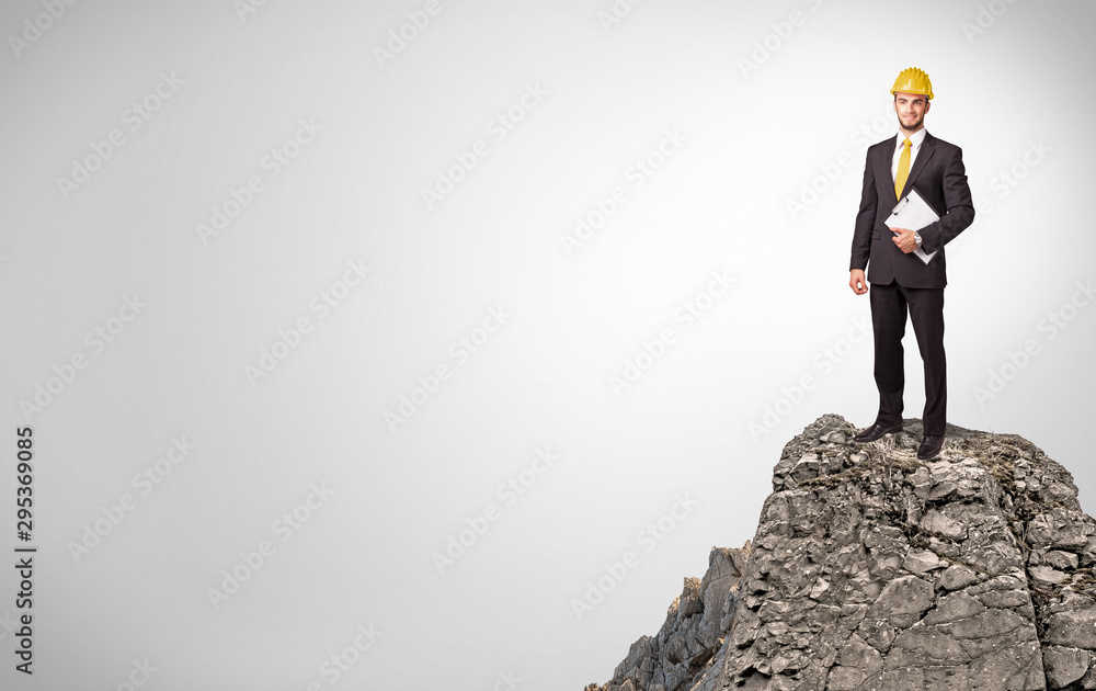 Young business person on the top of the rock with copy space