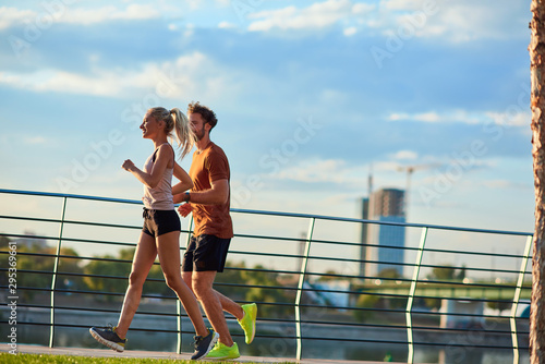 Modern woman and man jogging / exercising in urban surroundings near the river.