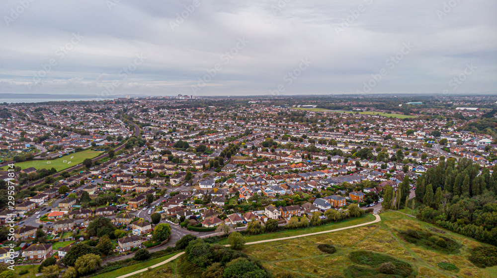 An aerial view of an urban area along a park under a grey sky and white clouds