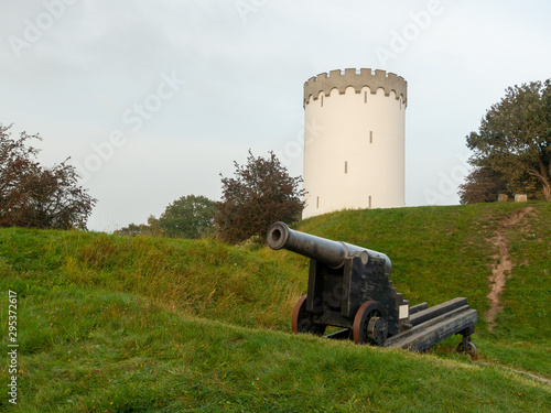 Old white water tower on rampart in city Fredericia, Denmark.Old bronze cannon on rampart in city Fredericia, Denmark.