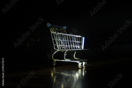 Empty shopping trolley on dark toned foggy background with some copy space. Financial crisis concept.