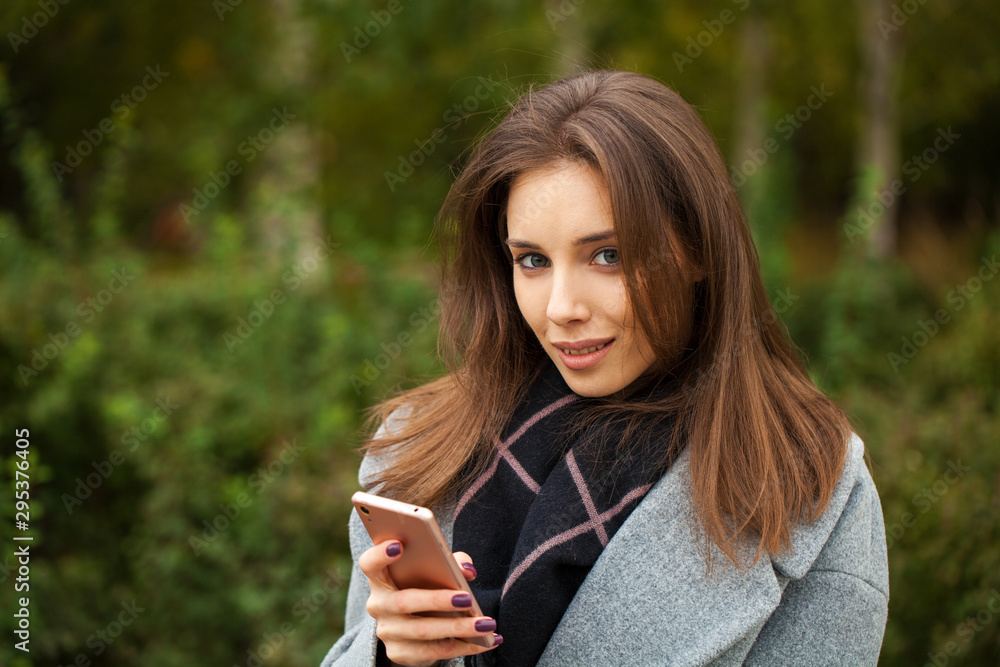 Young beautiful woman in a gray coat writes a message Young beautiful woman in a gray coat writes a message