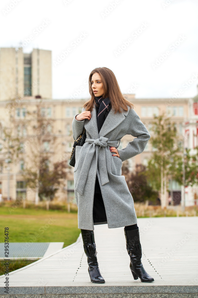 Portrait of young beautiful woman in gray coat posing in autumn park in Moscow