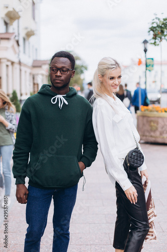 Happy interracial couple, black man and white woman walking in the city 