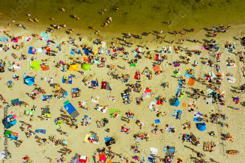 Top view of the beach in Gdansk, Poland. The beach is located on the shores of the Baltic Sea. Crowds of people swim and sunbathe on the Baltic Sea on a hot sunny day. 