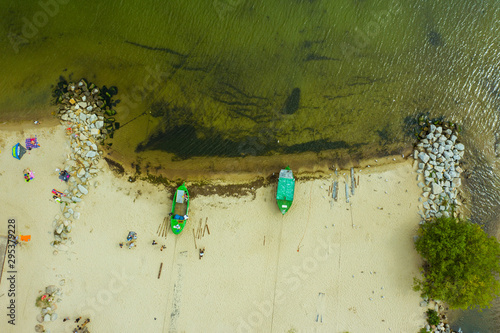 Suburb of Gdynia-Poland. Aerial view of fishing boats moored on the beach shore. Two green ships stand on the beach on a sunny summer day. 