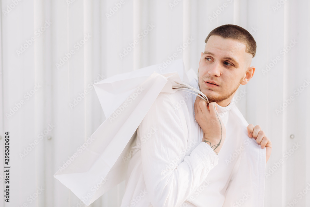 A stylish man wearing white after Black Friday shopping A stylish man wearing white after Black Friday shopping