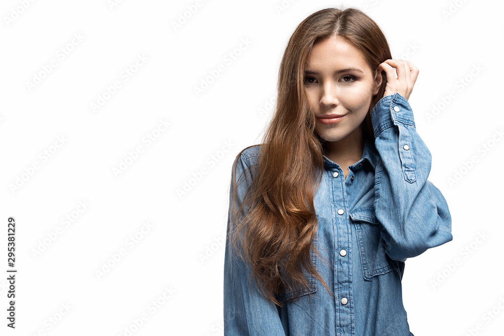 Portrait of shy lovely young woman in fashionable jean jacket. Adorable long-haired model posing in studio on white background. Copy space in left side. Fashion and beauty concept Portrait of shy lovely young woman in fashionable jean jacket. Adorable long-haired model posing in studio on white background. Copy space in left side. Fashion and beauty concept