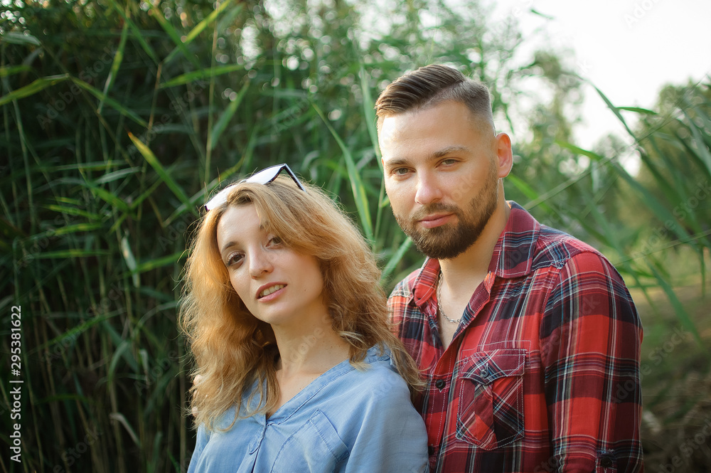 Close up portrait of young couple hugging and looking at the camera on green stems background, hipsters concept Close up portrait of young couple hugging and looking at the camera on green stems background, hipsters concept