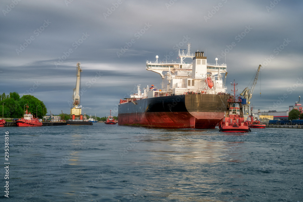 The Port of Gdansk, Poland, tugs enter the port of a large merchant ship