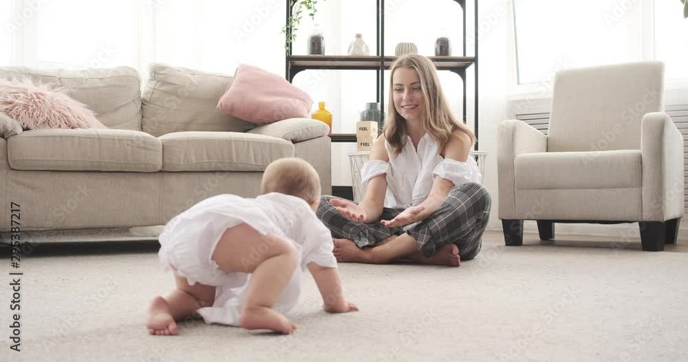 Cute baby girl crawling on carpet towards her mother at home Cute baby girl crawling on carpet towards her mother at home