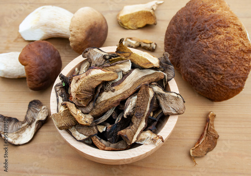 Dried mushrooms in a bowl surrounded by freshly picked boletus