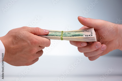 Close-up Of Two Male Hand's Holding Currency Bundle