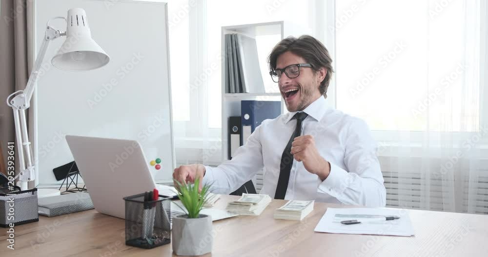 Rich businessman throwing cash dollars and celebrating success at office Rich businessman throwing cash dollars and celebrating success at office