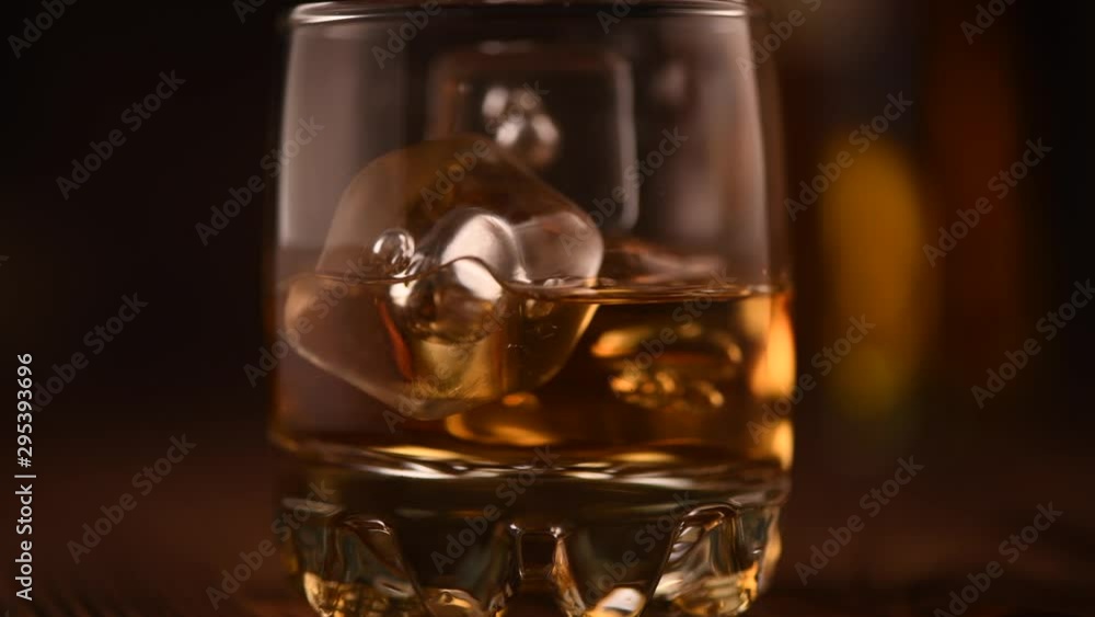 Whiskey. Irish whisky on the rocks. Glass of scotch with ice on wooden table closeup. 4K UHD video footage. 3840X2160 Whiskey. Irish whisky on the rocks. Glass of scotch with ice on wooden table closeup. 4K UHD video footage. 3840X2160