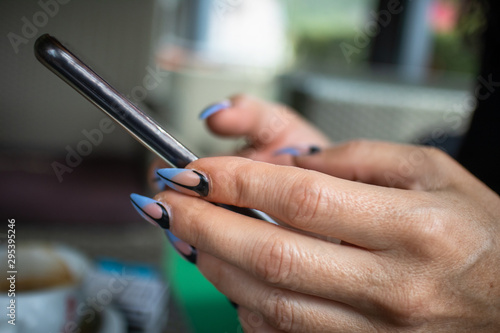 Woman s hands with manicured nails holding smartphone