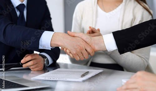 Business people shaking hands after contract signing at the glass desk in modern office. Unknown businessman  male entrepreneur with colleagues at meeting or negotiation. Teamwork  partnership and