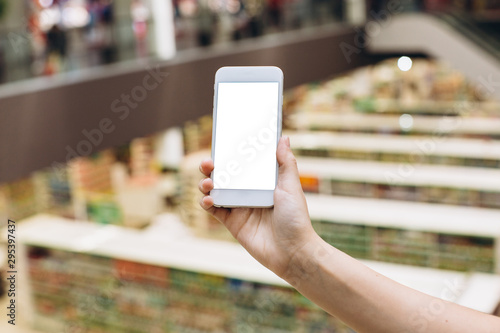 Hand using smartphone for doing business or banking or buying online on blur shopping mall background