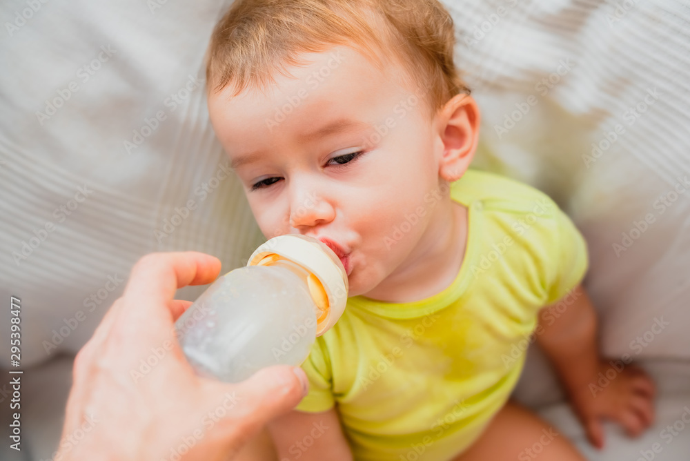 Adorable 1 year old baby drinks bottle formula drink for infant, helped by her single father. Adorable 1 year old baby drinks bottle formula drink for infant, helped by her single father.