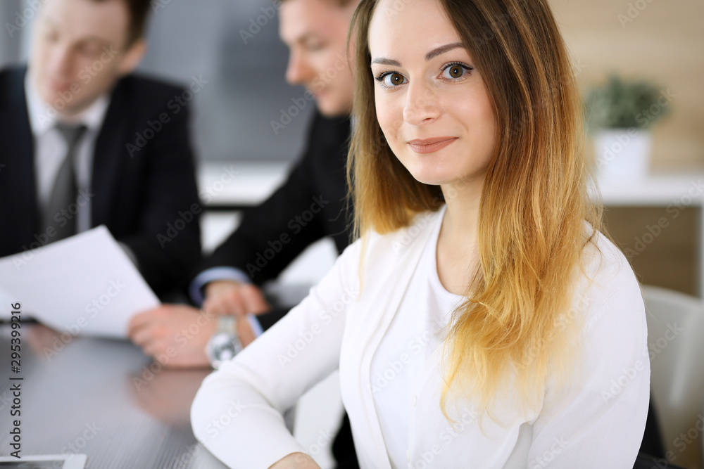 Business woman headshot at meeting in modern office. Unknown businesswoman sitting with colleagues at the background. Teamwork and partnership concept Business woman headshot at meeting in modern office. Unknown businesswoman sitting with colleagues at the background. Teamwork and partnership concept