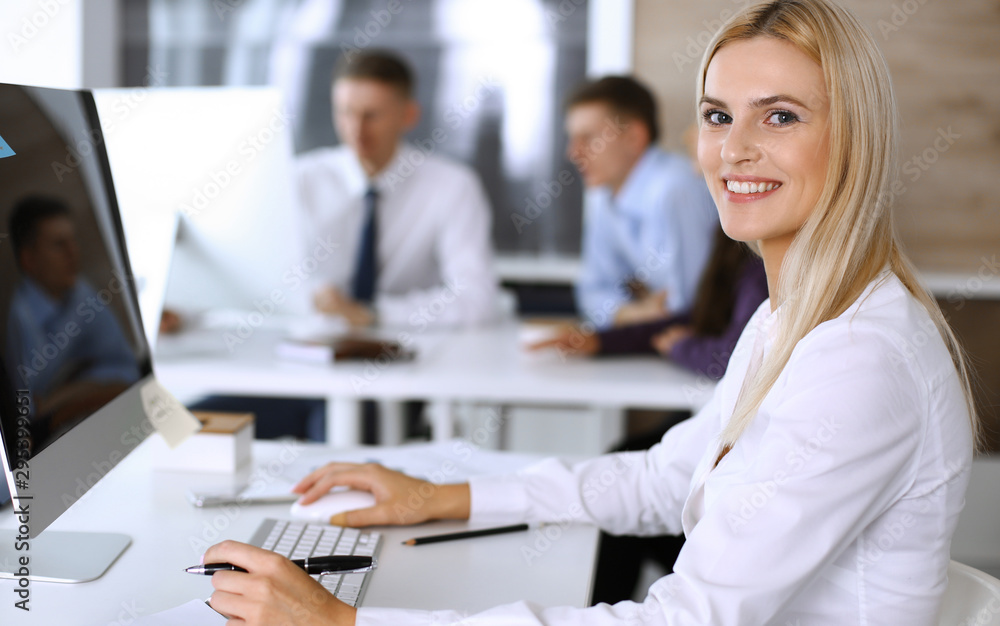 Business woman using computer at workplace in modern office. Secretary or female lawyer smiling and looks happy. Working for pleasure and success Business woman using computer at workplace in modern office. Secretary or female lawyer smiling and looks happy. Working for pleasure and success