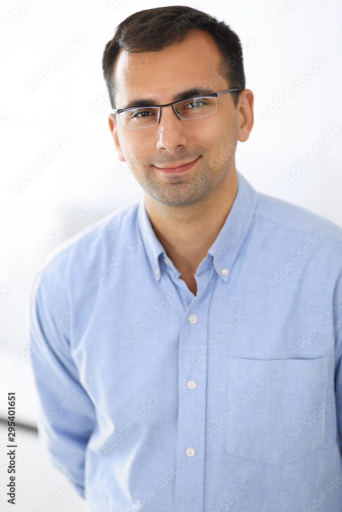 Businessman standing and looking at camera in office. Headshot of casual dressed adult guy happy smiling Businessman standing and looking at camera in office. Headshot of casual dressed adult guy happy smiling