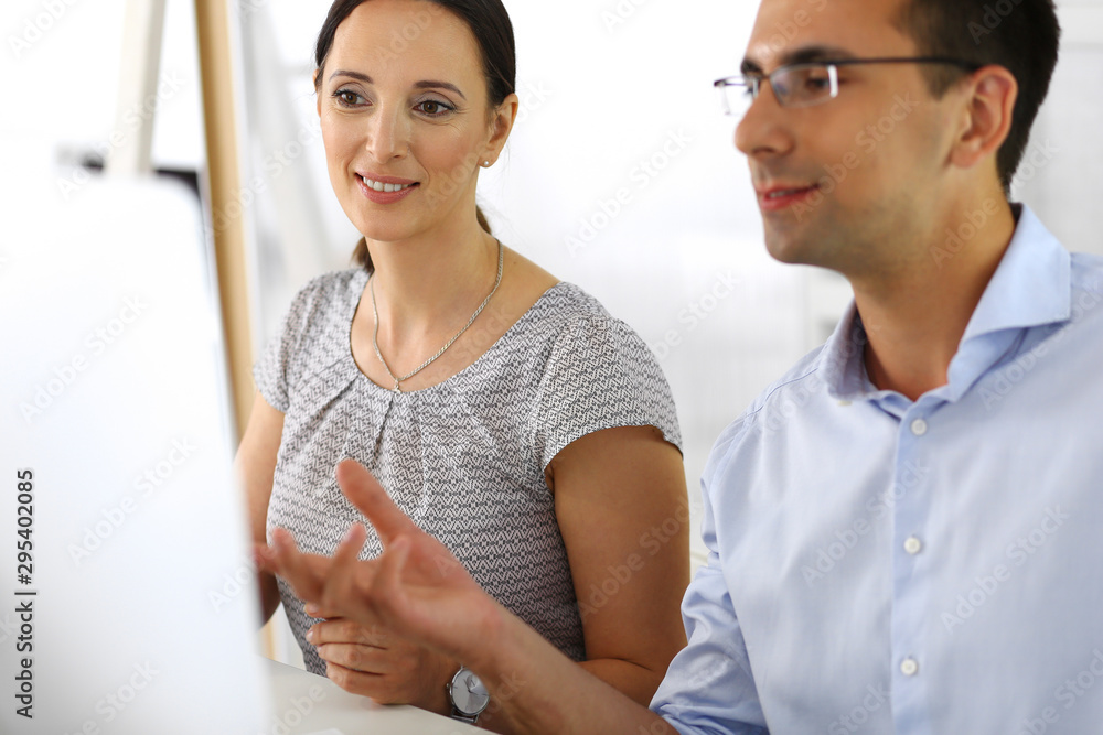 Business woman and businessman discussing questions while using a computer in modern office. Group of diverse people. Teamwork, partnership and business concept Business woman and businessman discussing questions while using a computer in modern office. Group of diverse people. Teamwork, partnership and business concept