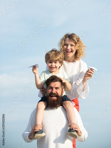 Childcare. Happy family - father mother and child on meadow with a toy paper airplane in the summer on the nature background. Parenthood. Family like summer time together.