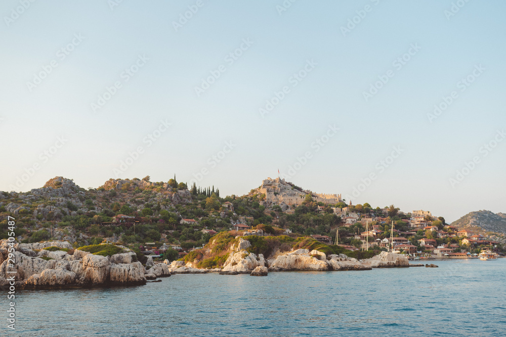 The village of Kalekoy seen south from a drone aerial perspective, with the Byzantine Simena castle in the centre near Kekova island in the Antalya Province of Turkey. Turkish flag flying at the top