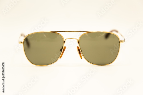 close up front view of old vintage sunglasses on white background . gold frame and black glass . old-fashioned eye wearing classic collection .