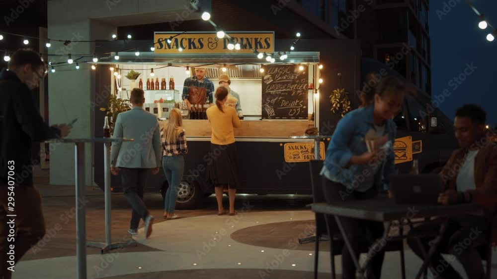Food Truck Employee Hands Out Freshly Made Beef Burgers, Fries and Cold Drinks to Happy Young Hipster Customers. Commercial Truck Selling Street Food in a Modern Cool Neighbourhood. Food Truck Employee Hands Out Freshly Made Beef Burgers, Fries and Cold Drinks to Happy Young Hipster Customers. Commercial Truck Selling Street Food in a Modern Cool Neighbourhood.