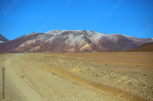 Bolivia, Andes in the Potosi province. Wide dusty valley in the desert with mountains in the background and clear blue sky. 