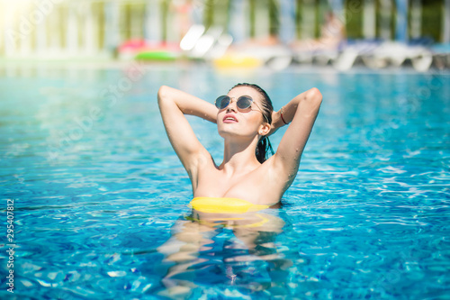 Young woman in yellow bikini posing in the water with sunglasses. Summer relax.