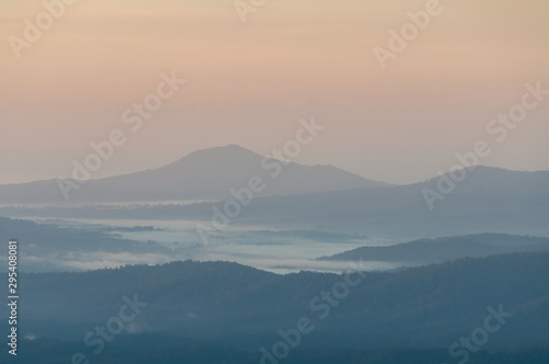 Beautiful nature landscape with mountains in a fog on sunrise © Olga K