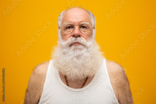 Old man with a long beard on a yellow background. Senior with full white beard. Old man with a long beard with sadness. photo