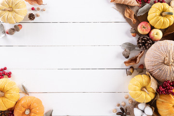 Top view of Autumn maple leaves with Pumpkin and red berries on white wooden background. Thanksgiving day concept.
