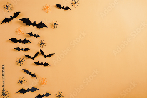 Top view of Halloween crafts, black paper ghost, spider and bats flying over orange background with copy space for text. halloween concept. © Siam