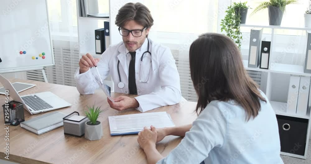 Doctor speaking with woman patient about dental xray test result at clinic Doctor speaking with woman patient about dental xray test result at clinic