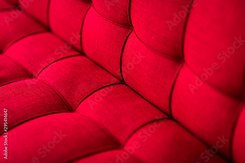 Close up shot of elegant red couch with buttons in a living room. Modern furniture concept. Texture for background and design. Horizontal shot