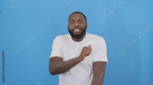 Portrait of happy african man having stylish afro hairdo and mustache dancing with arms while listening to music, isolated over white background slow motion. Concept of emotions 4K