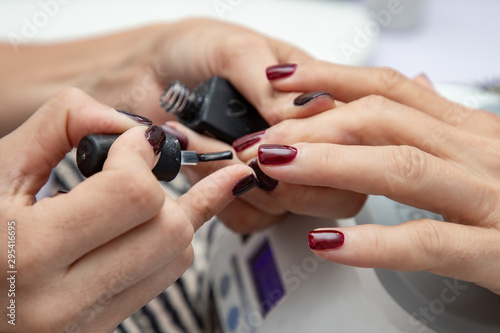 Manicure at the beauty salon  nail polish  red color  manicure master at workplace