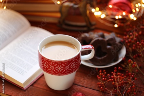 Winter tea. Winter books. cup of hot tea, books, Christmas gingerbread cookies, decor and shining garland on a wooden background.Books about Christmas. Winter holidays.