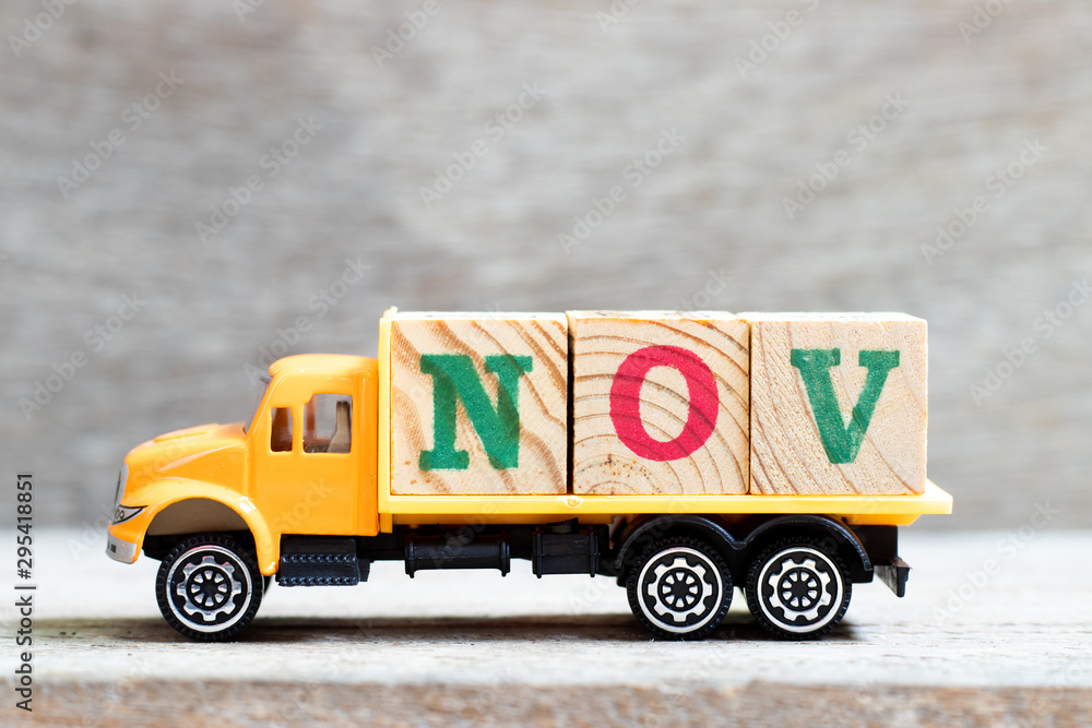 Truck hold letter block in word nov on wood background (Concept for month November)