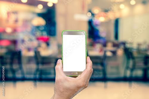 hand holding mobile smart phone with restaurant blur background,vintage effect style